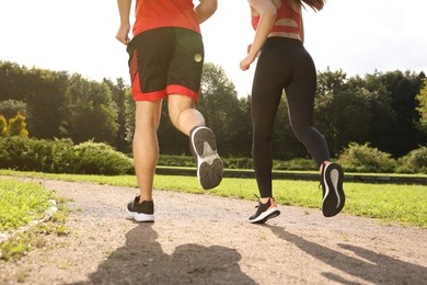 Photo of Healthy lifestyle. Couple running in park on sunny day, closeup