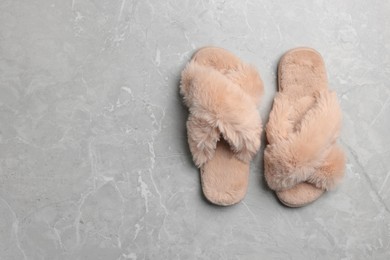 Pair of soft slippers on grey marble floor, top view. Space for text