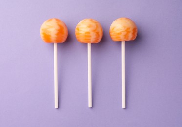 Photo of Tasty lollipops on violet background, flat lay