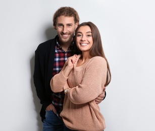 Photo of Young woman in warm sweater and man wearing knitted cardigan on white background
