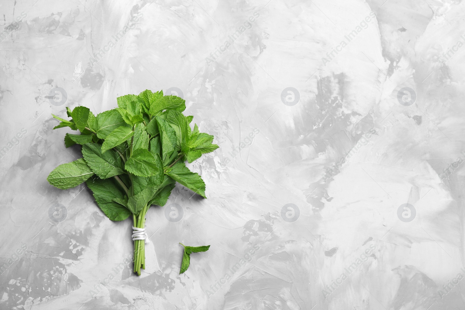 Photo of Bunch of fresh mint on grey marble table, top view. Space for text