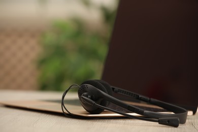 Photo of Headset and laptop on table indoors, closeup. Hotline concept