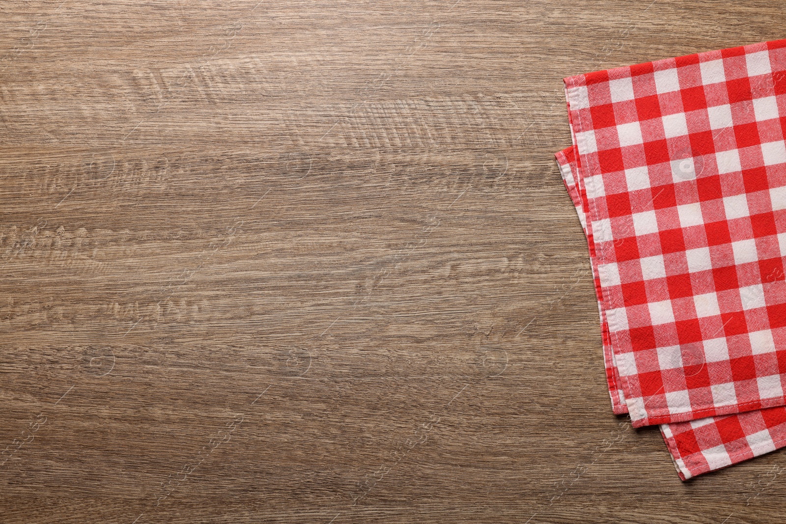 Photo of Checkered tablecloth on wooden table, top view. Space for text