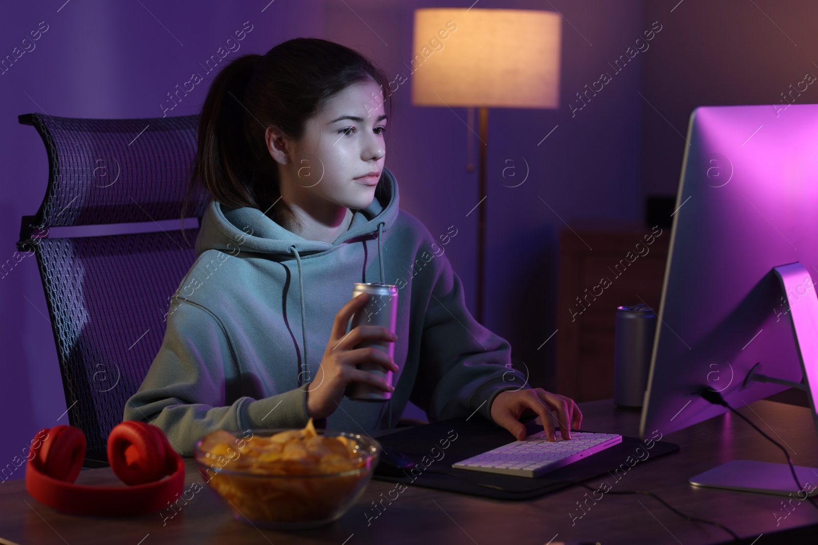 Photo of Girl with energy drink playing computer game at table in room