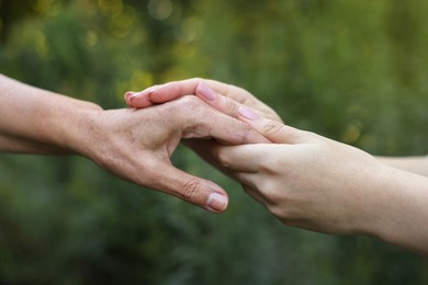 Photo of Trust and support. People joining hands outdoors, closeup