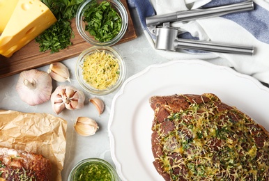 Photo of Loaves of tasty homemade garlic bread with cheese and herbs on grey table, flat lay