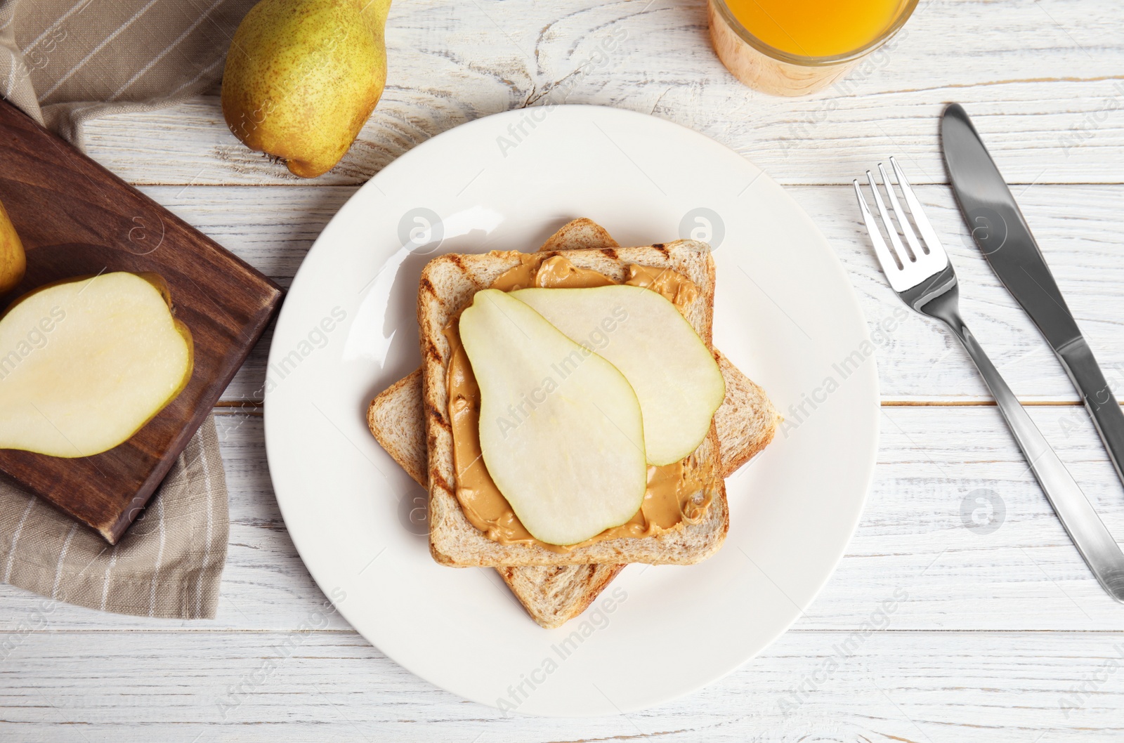 Photo of Slice of bread with peanut butter and pear on white wooden table, flat lay