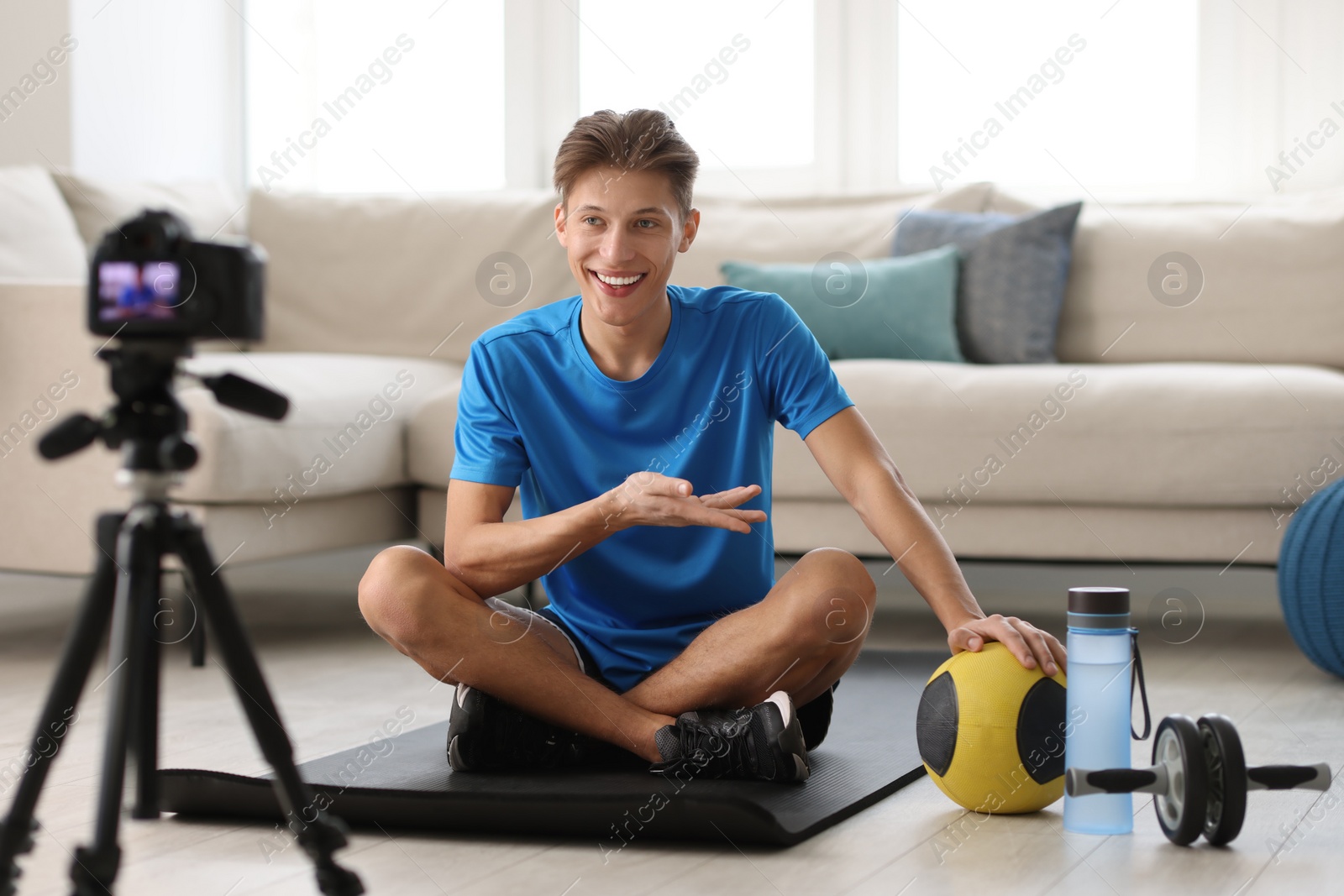 Photo of Smiling sports blogger recording fitness lesson with camera at home