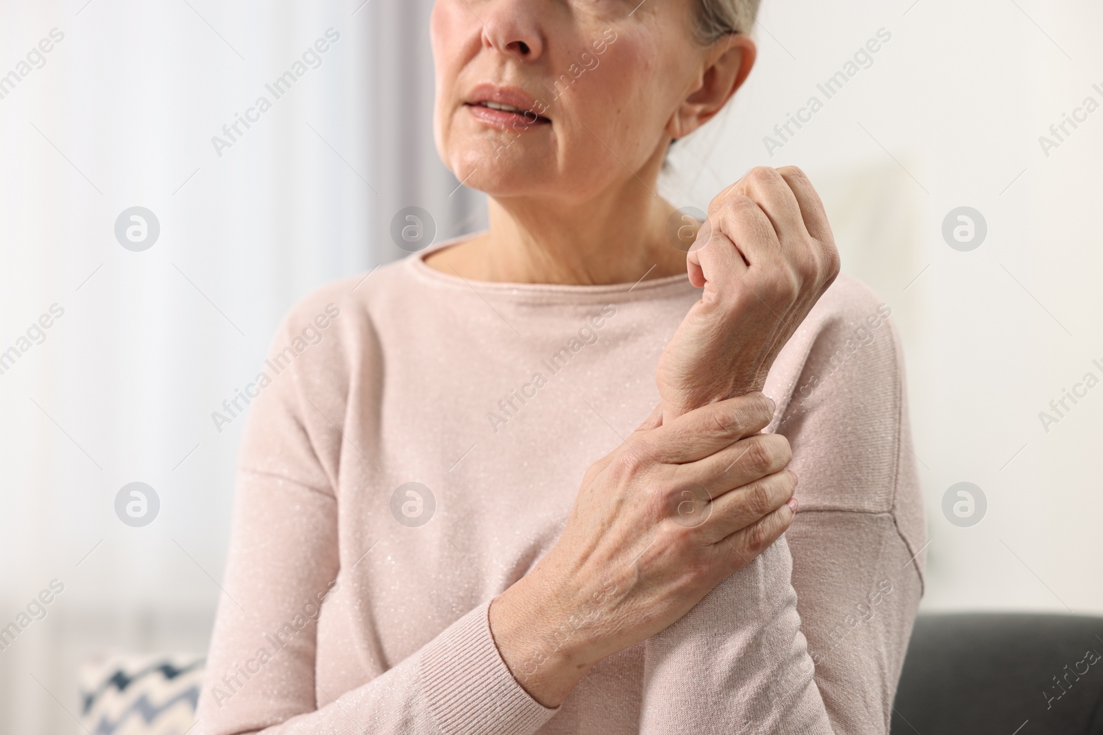 Photo of Arthritis symptoms. Woman suffering from pain in wrist at home, closeup