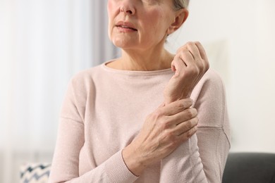 Photo of Arthritis symptoms. Woman suffering from pain in wrist at home, closeup