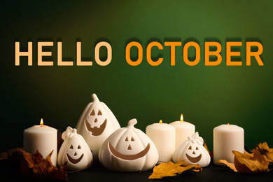 Image of Hello October card. Jack-o-Lantern candle holders as Halloween decor and autumn dry leaves on black table