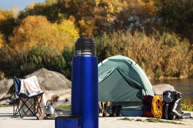 Image of Modern thermos outdoors on sunny day. Camping season 