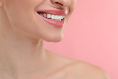 Photo of Young woman with beautiful smile on pink background, closeup