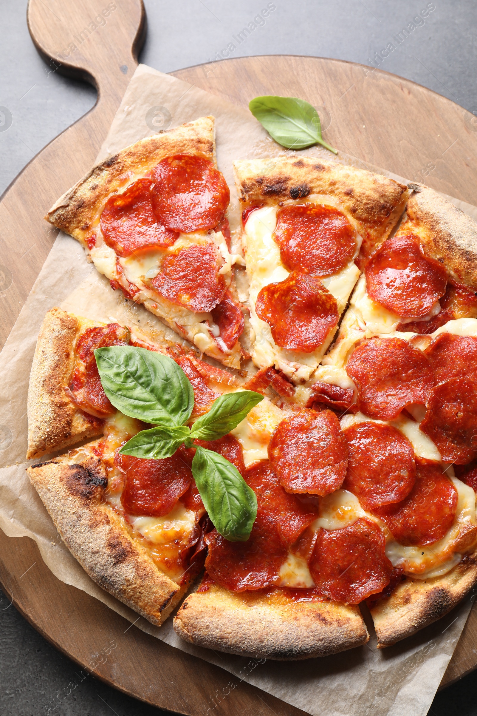 Photo of Tasty pepperoni pizza with basil on grey table, top view