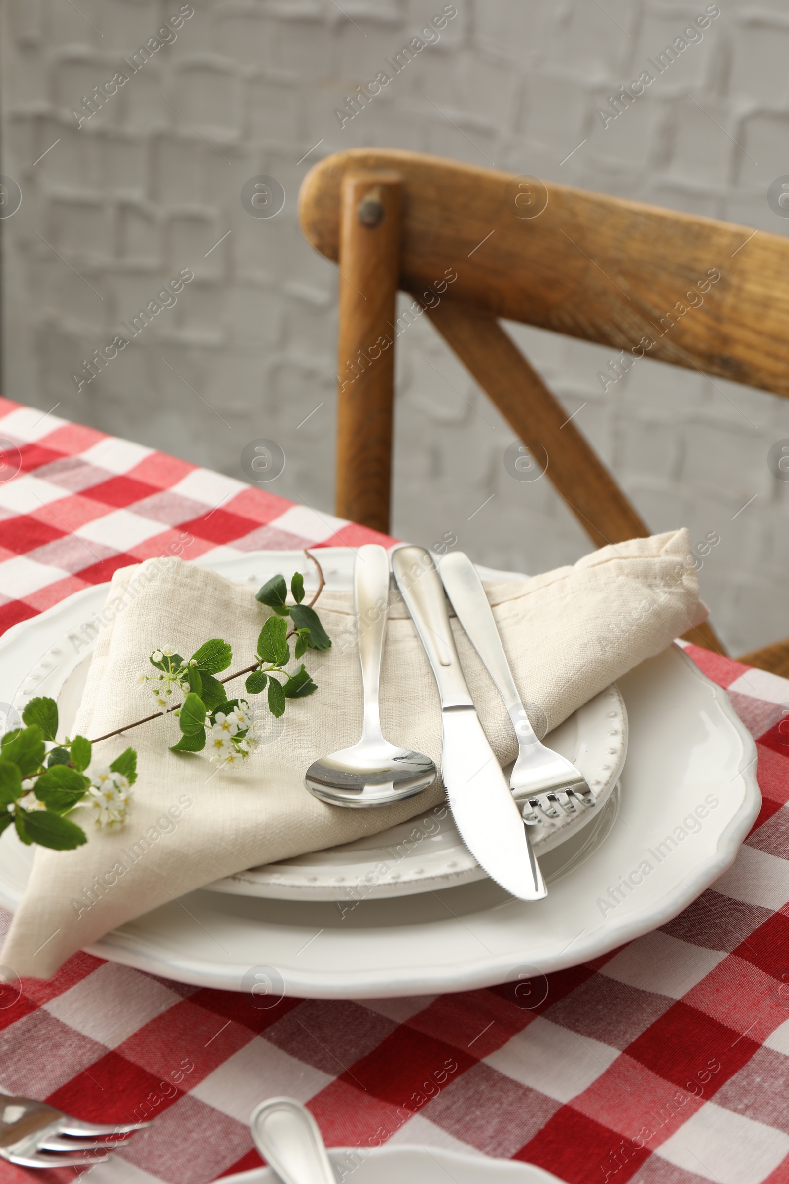 Photo of Stylish setting with cutlery, plates, napkin and floral decor on table