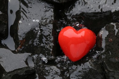 Photo of Red decorative heart on stones and water, top view. Space for text