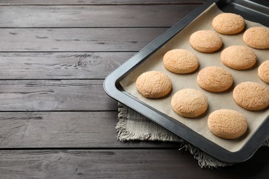 Photo of Baking sheet with delicious sugar cookies on black wooden table, space for text