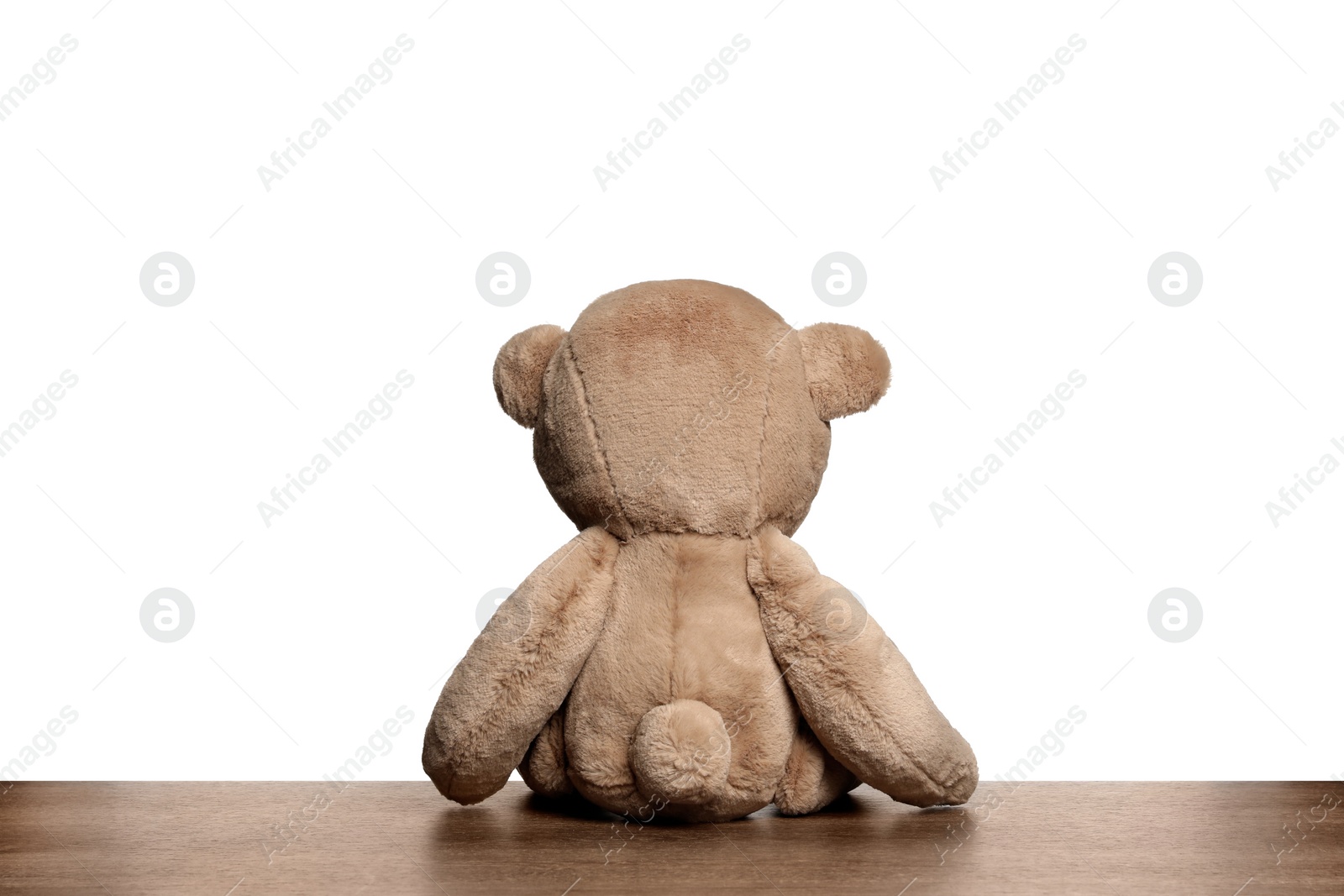 Photo of Cute teddy bear on wooden table against white background, back view