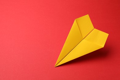 Photo of Handmade yellow paper plane on red background, space for text