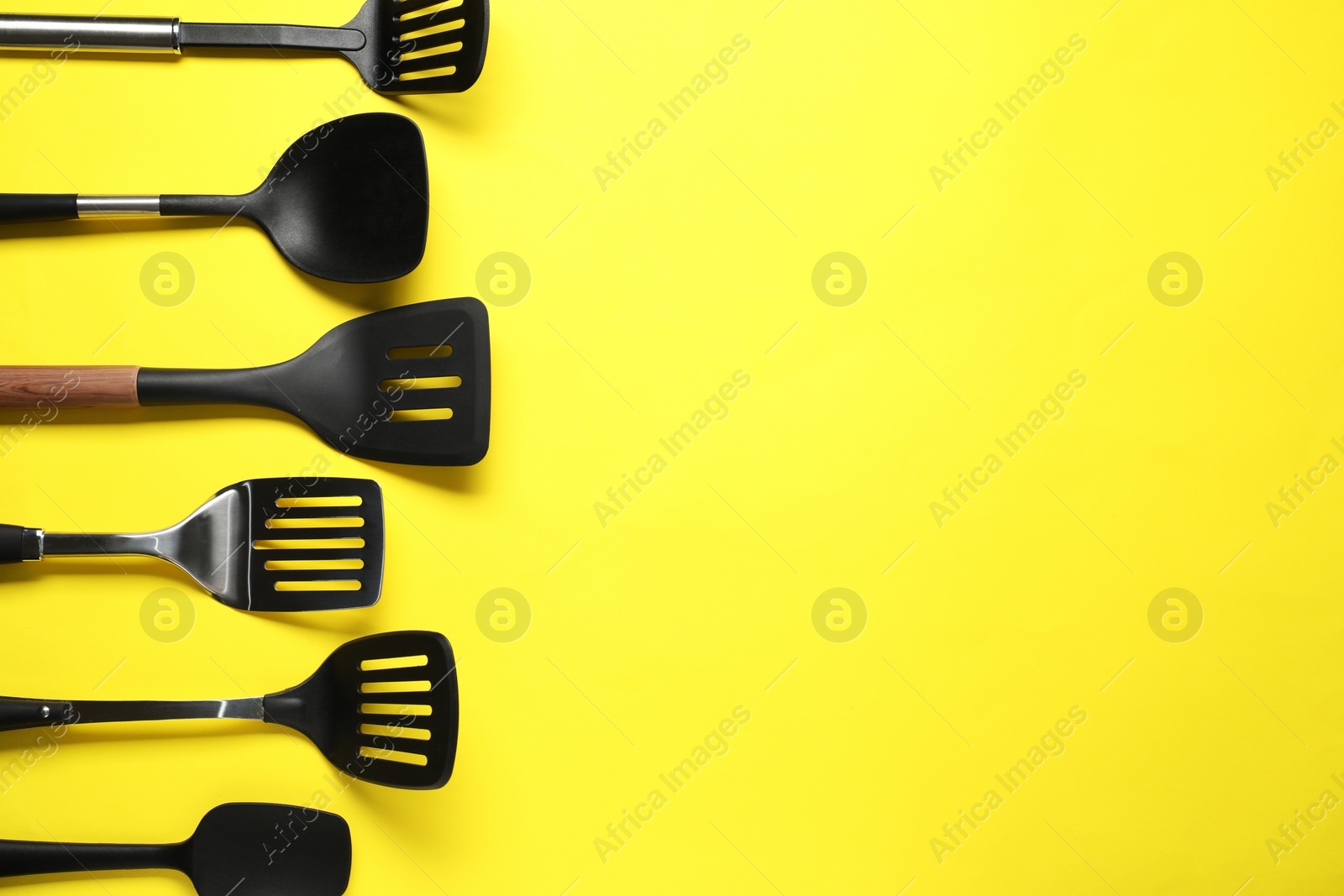 Photo of Different spatulas on yellow background, flat lay. Space for text