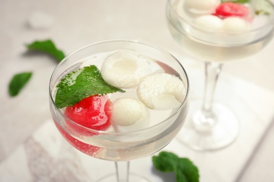 Photo of Glass with tasty melon and watermelon ball drink on light table, closeup