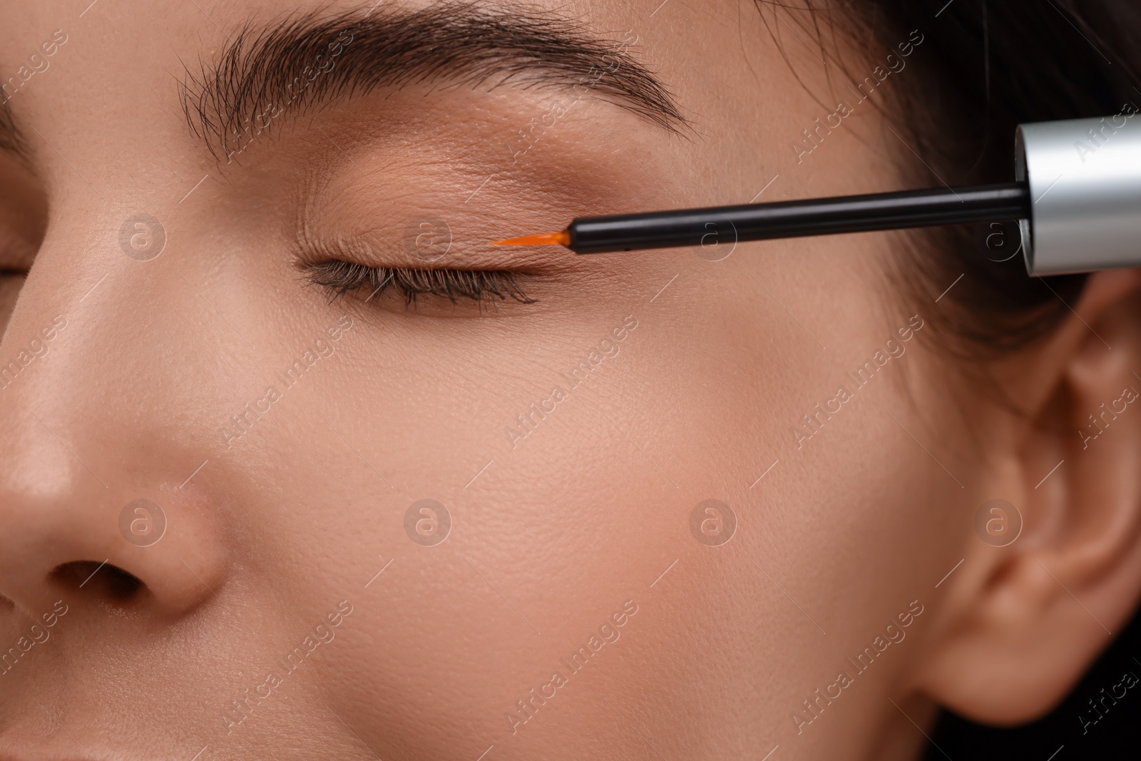 Photo of Woman applying serum onto her eyelashes, closeup. Cosmetic product