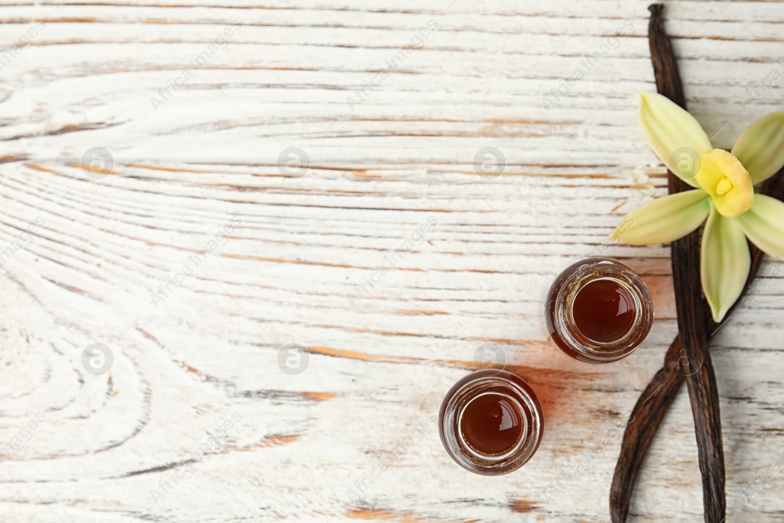 Photo of Flat lay composition with vanilla extract on white wooden table. Space for text