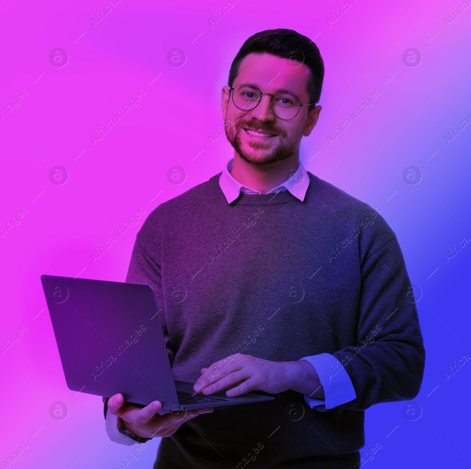 Image of Handsome man with laptop in neon lights