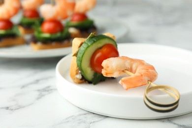 Photo of Tasty canape with shrimp, cucumber and tomatoes on white marble table, closeup. Space for text