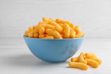 Photo of Many tasty cheesy corn puffs on white marble table