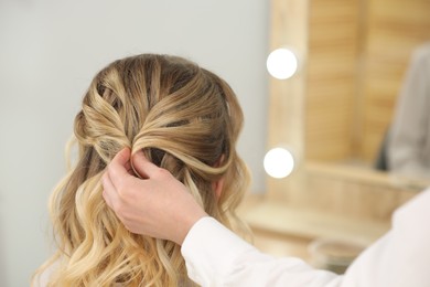 Hair styling. Professional hairdresser working with client in salon, closeup