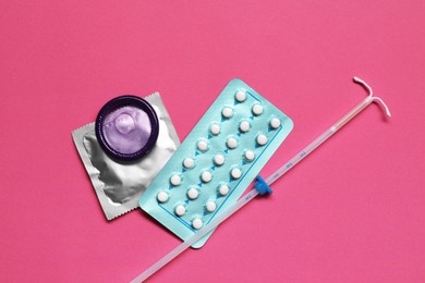 Photo of Contraception choice. Pills, condoms and intrauterine device on magenta background, flat lay