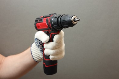 Photo of Handyman holding electric screwdriver on grey background, closeup