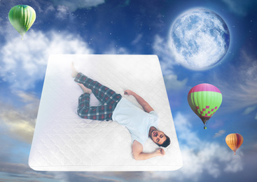 Image of Sweet dreams. Blue cloudy sky with full moon and hot air balloons around sleeping young man 