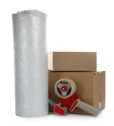 Photo of Bubble wrap roll, cardboard boxes and tape dispenser on white background