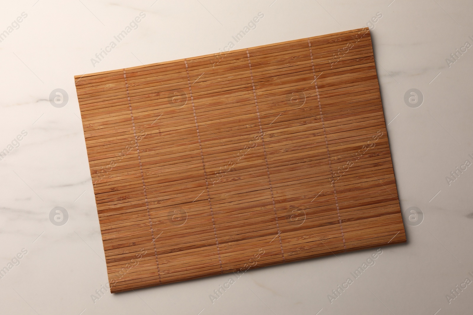 Photo of Bamboo mat on white marble table, top view. Space for text