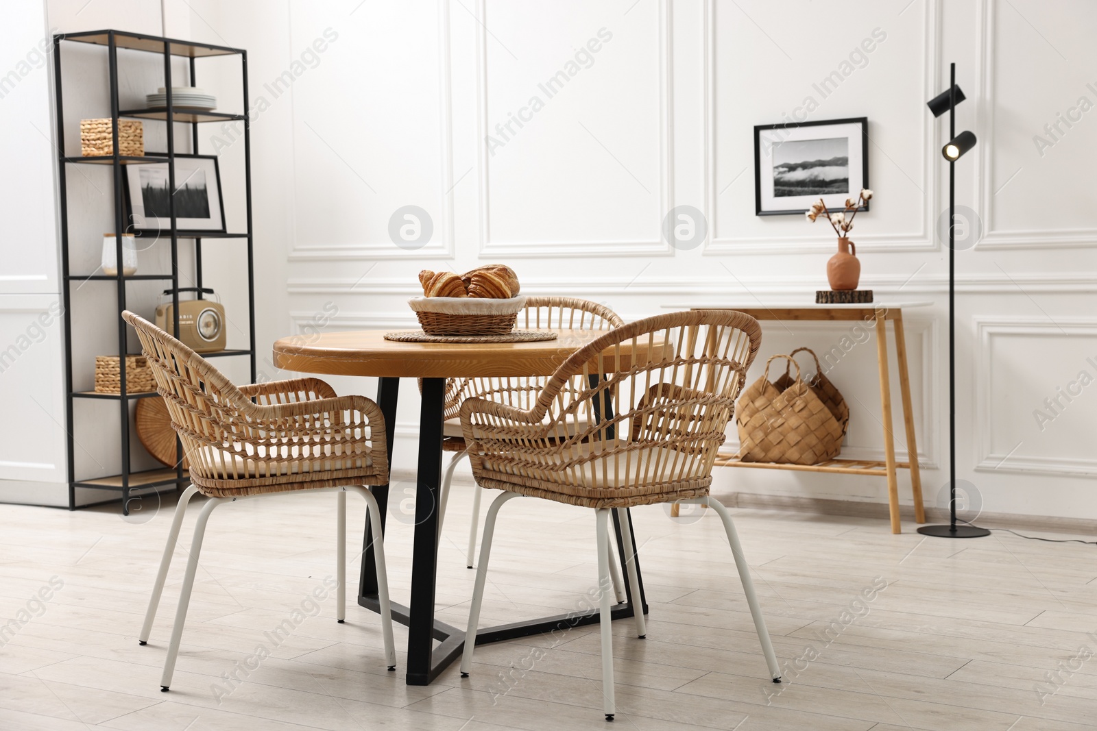 Photo of Dining room interior with wooden table and wicker chairs