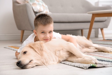 Photo of Cute little child with his pet on floor at home