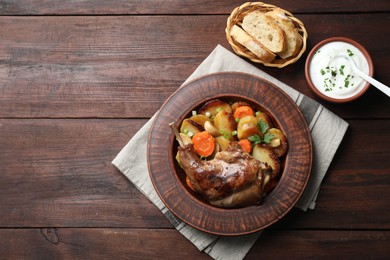 Photo of Tasty cooked rabbit meat with vegetables served on wooden table, flat lay. Space for text