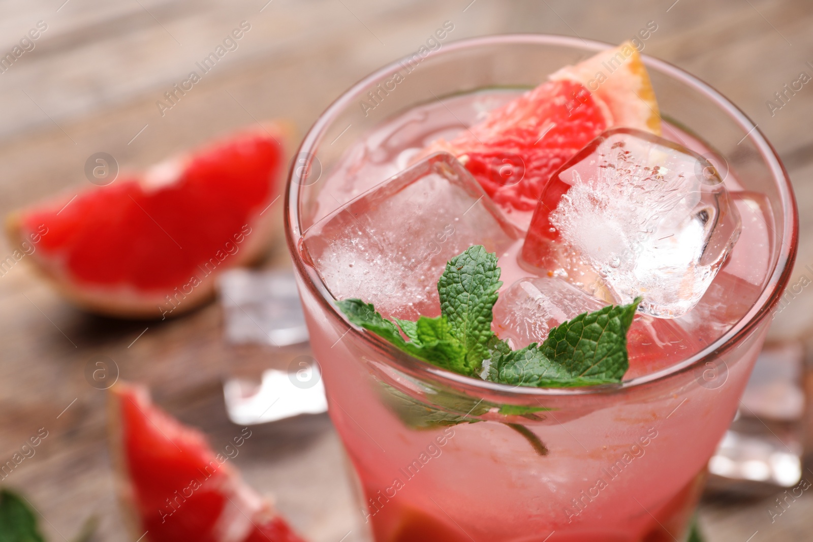 Photo of Glass of refreshing drink with grapefruit and mint on wooden table, closeup view. Space for text