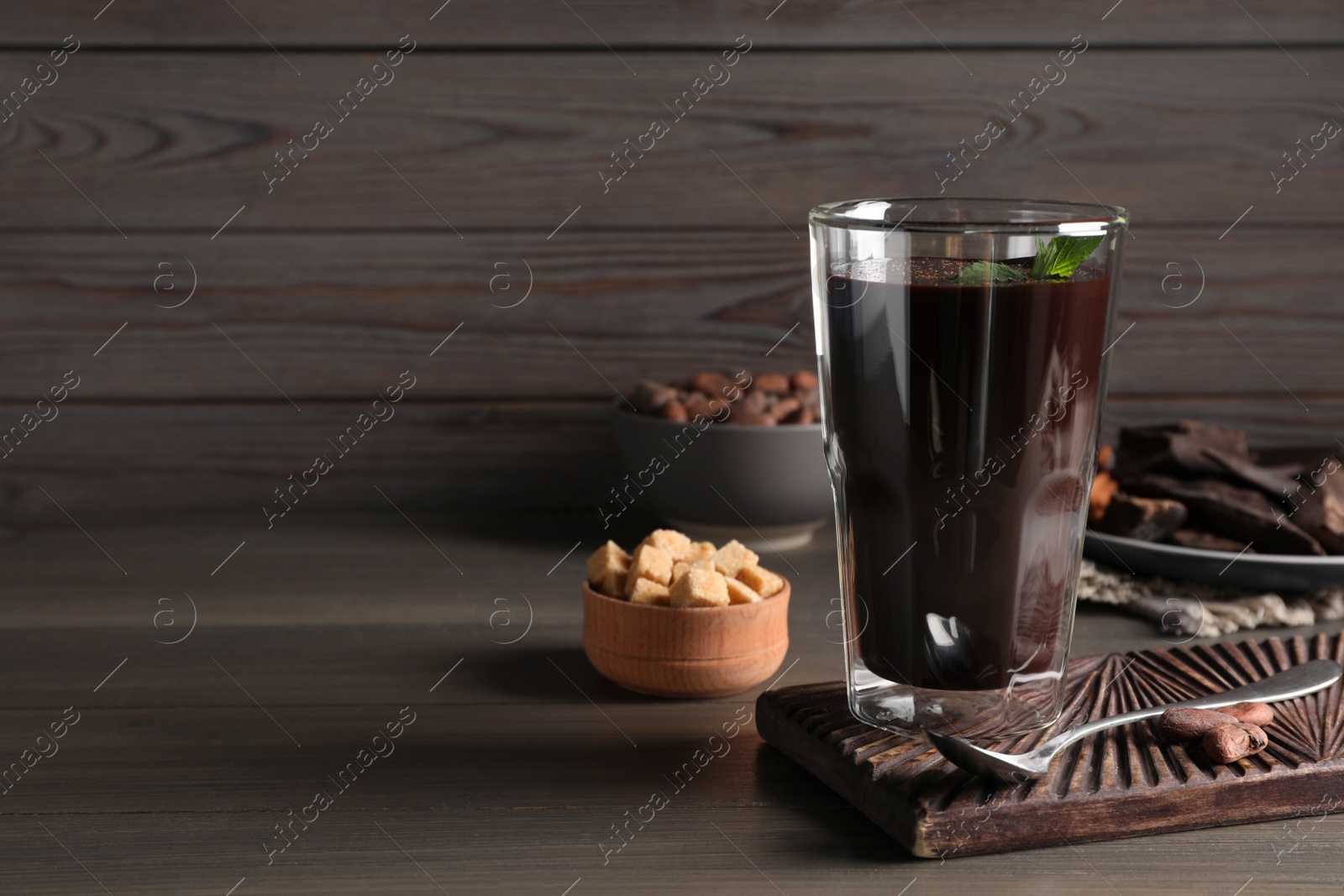 Photo of Glass of delicious hot chocolate on wooden table. Space for text