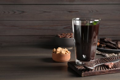 Photo of Glass of delicious hot chocolate on wooden table. Space for text