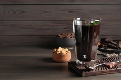 Glass of delicious hot chocolate on wooden table. Space for text