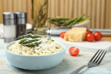Photo of Delicious risotto with asparagus and cheese on wooden table. Space for text
