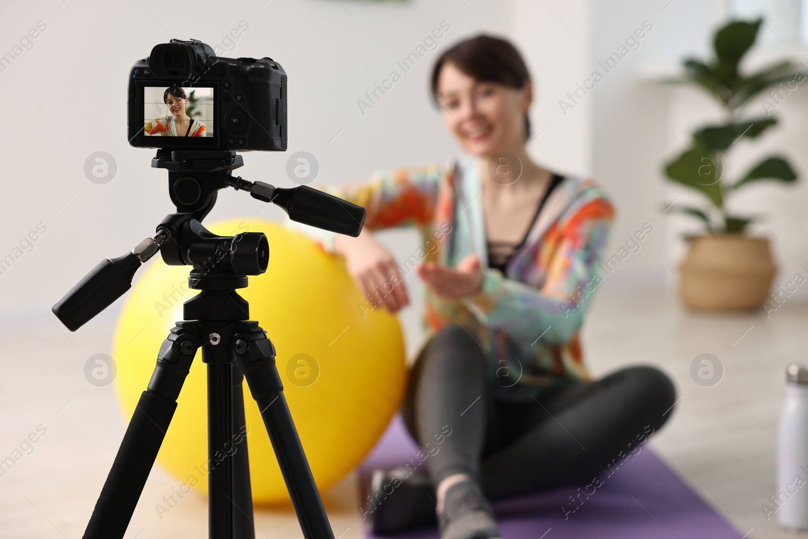 Photo of Happy sports blogger recording fitness lesson at home, focus on camera