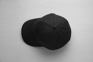 Photo of Stylish black baseball cap on light grey background, top view