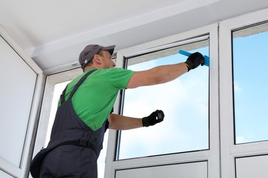 Worker installing double glazing window indoors, low angle view