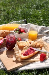 Blanket with different products on green grass. Summer picnic