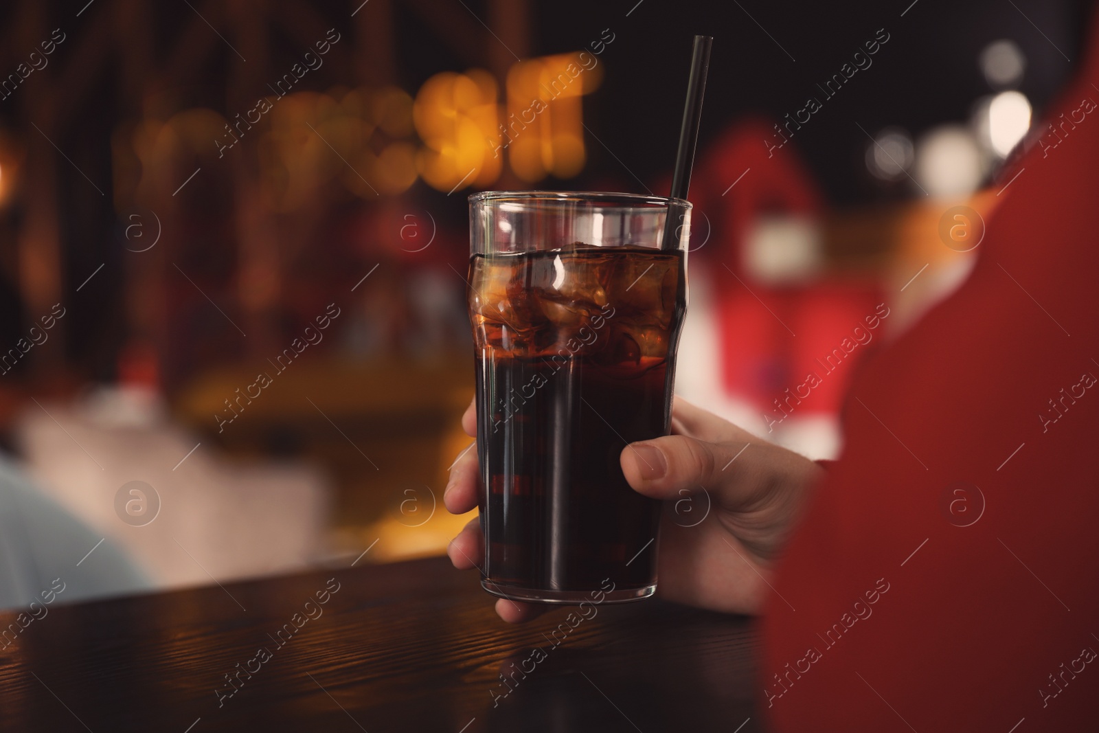 Photo of Man holding glass of refreshing cola at table indoors, closeup. Space for text