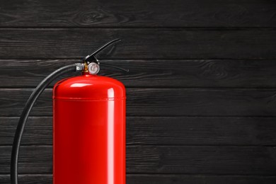 Fire extinguisher against wooden wall. Space for text